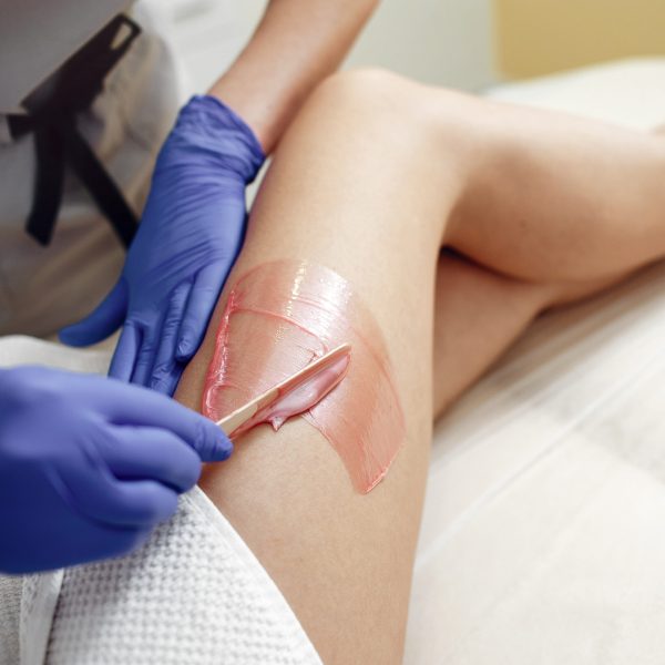 Beautiful girl doing hair removal. Woman in beauty salon